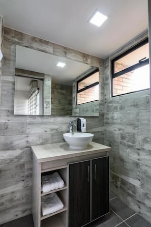 Un bany amb un mirall gran, un lavabo i un armari.