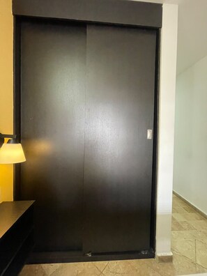 A closed door with a handle, a lamp to the left, and a tiled floor. - CV hotel medellin  (Medellin)