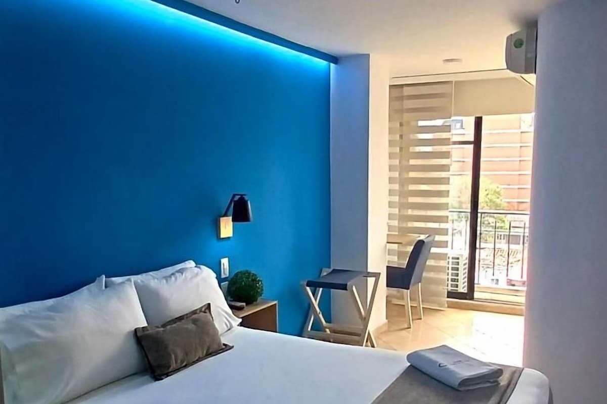 Habitació d'hotel amb un llit, escriptori i una cadira.