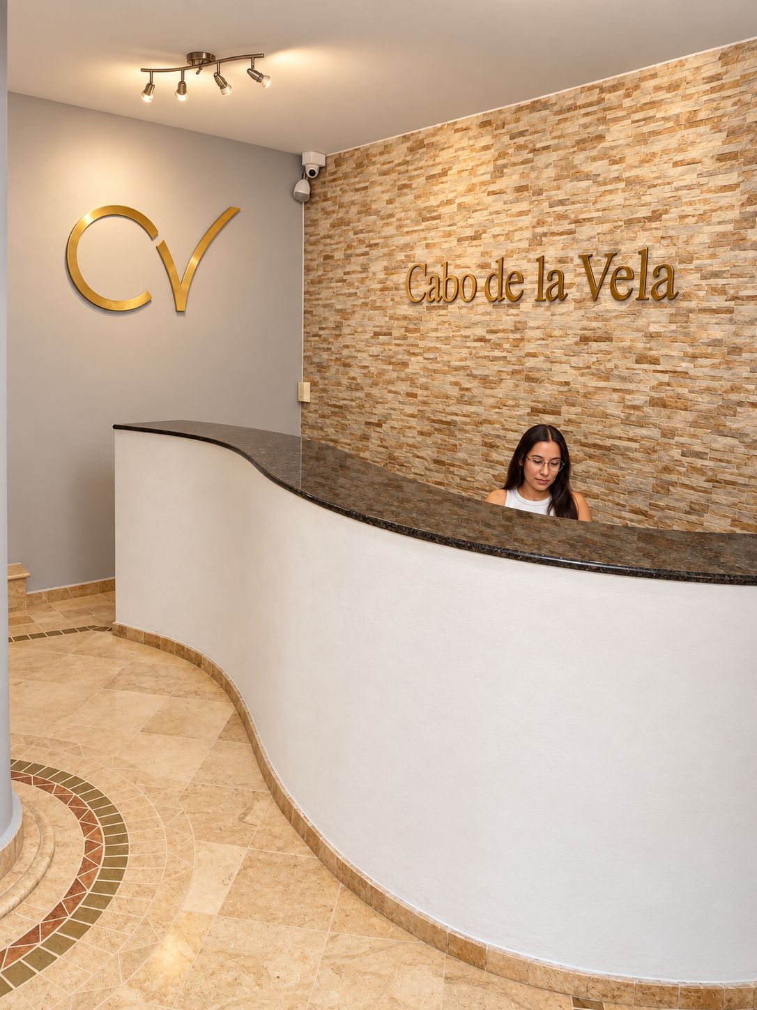 Un comptoir d’accueil avec un mur en pierre en arrière-plan et une enseigne indiquant « Cabo de la Vela ».