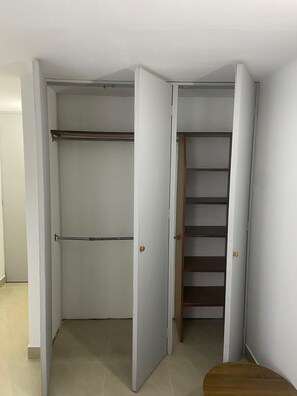 A walk-in closet with open doors, revealing shelves and a wooden stool. - Private apartment ideal for working, Downtown Medellín (Medellín)