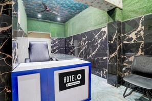 A hotel reception desk with a 'HOTELO' sign, a ceiling fan, and a green wall. - Hotel O Mathura Janam Bhumi Link Road (Mathura)