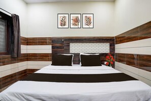 A hotel room with a bed, a nightstand, a window with curtains, and a wall with three framed pictures. - Hotel O Mathura Janam Bhumi Link Road (Mathura)