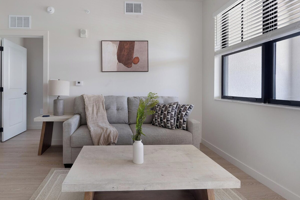 A modern living room with a sofa, a coffee table, and a painting on the wall.