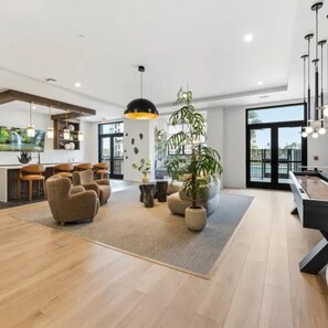 Uma sala de estar espaçosa com mesa de bilhar, assentos confortáveis e uma grande janela com vista para o exterior.