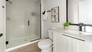 A modern bathroom with a glass shower enclosure, a toilet, a sink with a mirror, and a small potted plant. - Landing Incredible 1bd, Gym, Clubhouse (North Fort Myers)