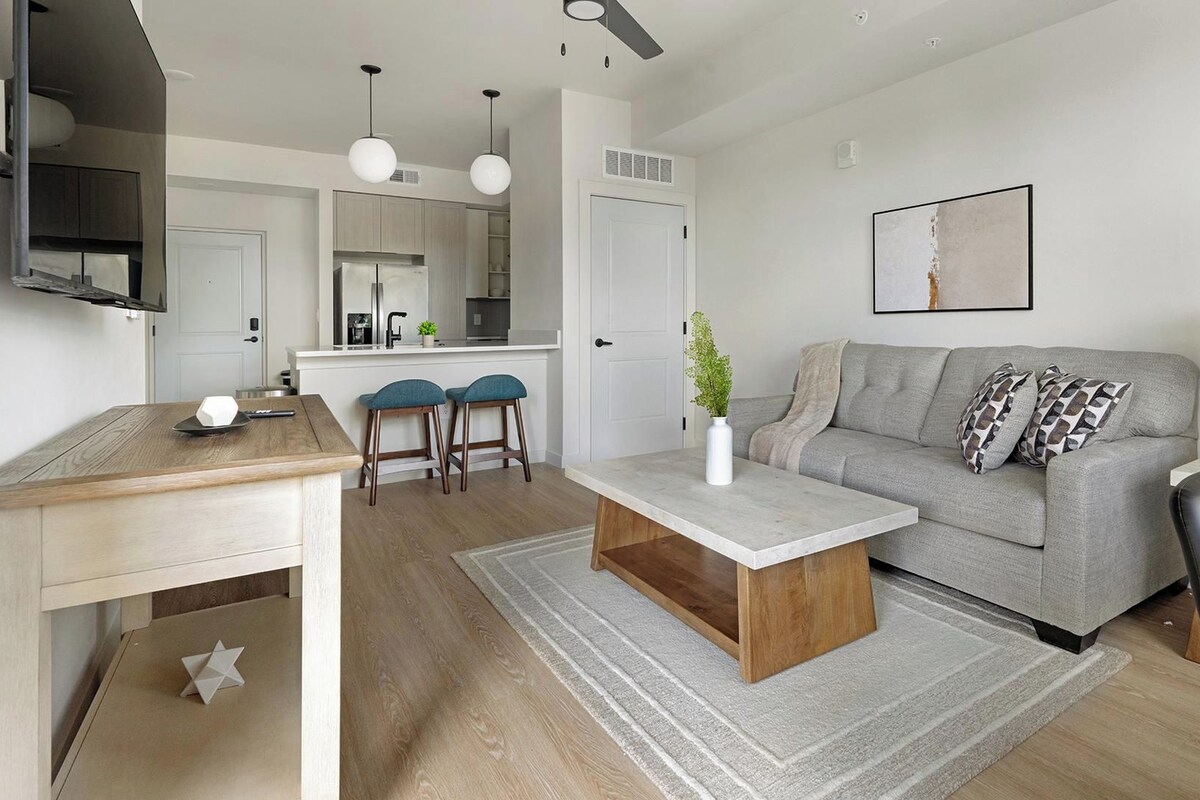 A modern living room with a sofa, coffee table, and a TV mounted on the wall.
