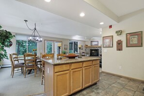A spacious kitchen with a central island, wooden cabinets, and a dining area with chairs and a table. - Creekside Frisco Retreat 4 Private Suites, Pool & Hot Tubs (Frisco)
