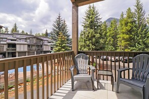 Ein Balkon mit zwei Adirondack-Stühlen, Blick auf einen Parkplatz und ein Gebäude mit zahlreichen Fenstern und Balkonen.