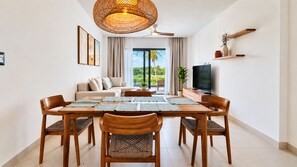 A modern living room with a dining area, large windows, and a ceiling fan. - Born | 2-bedroom modern apartment with pools (Bávaro)