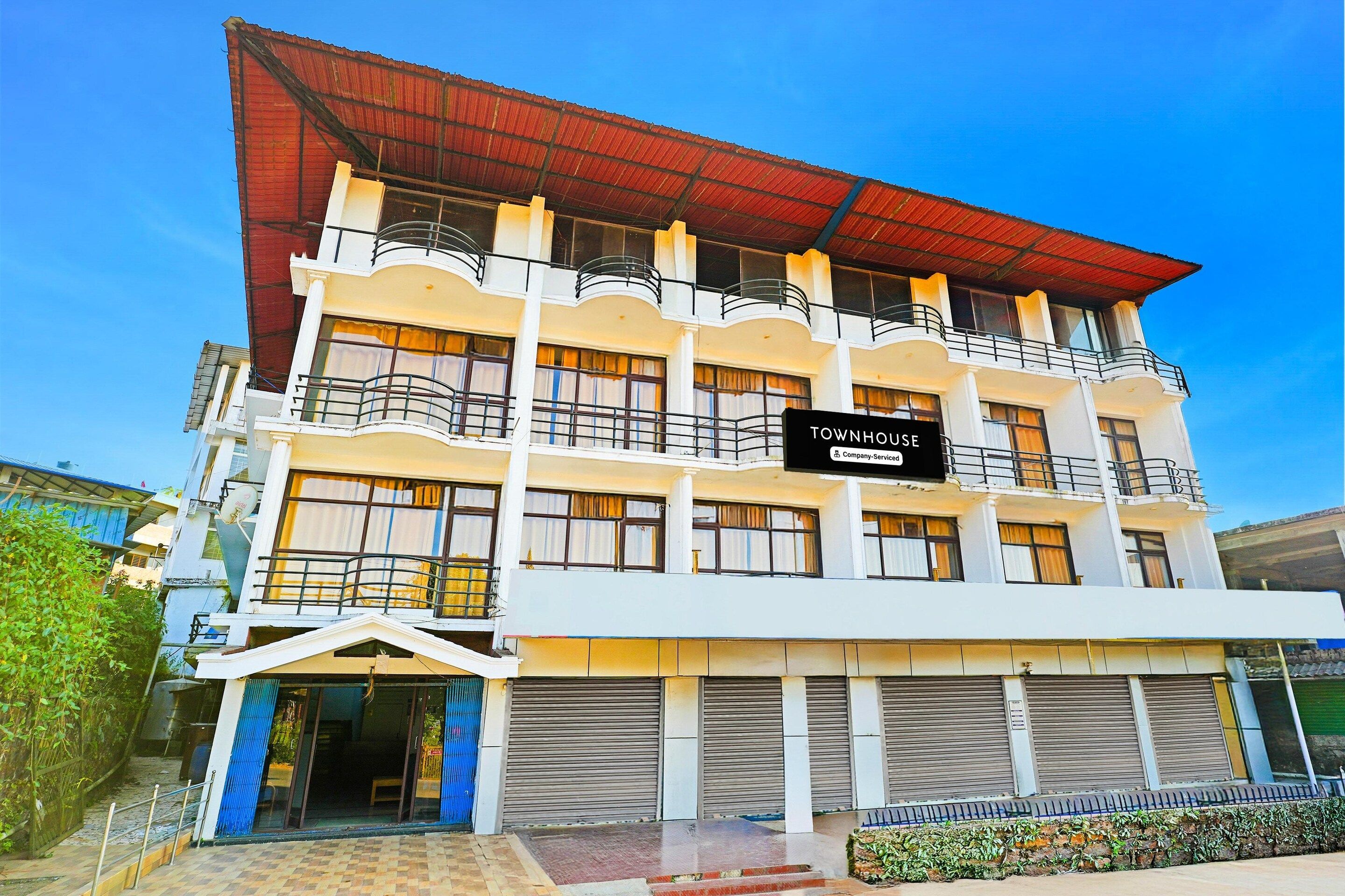 A multi-story building with balconies, a sign indicating 'Townhouse Company Service,' and a gated entrance.