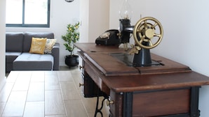 A room with a wooden desk, a globe, a sewing machine, a sofa, and a window. - Cantinho do Calhau (Lagoa)