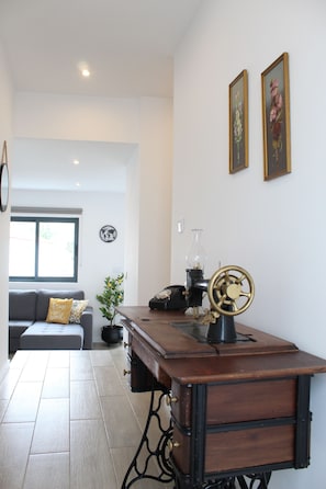 Ein Zimmer mit einem Holztisch, einem Globus, einer Nähmaschine, einem Sofa und einem Fenster.