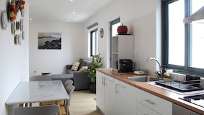 A modern kitchen with a dining area, a sofa, and a view of the outdoors. - Cantinho do Calhau (Lagoa)