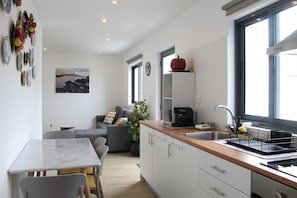 Eine moderne Küche mit Essbereich, einer Couch und Blick ins Freie.