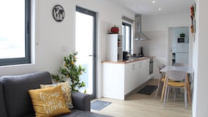 A modern living room with a grey sofa, a decorative pillow, a small plant, and a world map clock on the wall. - Cantinho do Calhau (Lagoa)