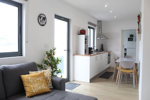 Ein modernes Wohnzimmer mit einem grauen Sofa, einem Zierkissen, einer kleinen Pflanze und einer Wanduhr mit Weltkarte.