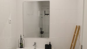 A bathroom with a white vanity, a mirror, a shower, and a wooden ladder leaning against the wall. - Cantinho do Calhau (Lagoa)