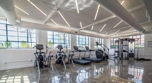Un gimnasio con cintas de correr, elípticas y una zona de pesas.