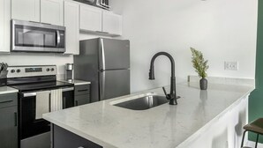 Una cocina moderna con electrodomésticos de acero inoxidable, encimera de mármol y grifo negro.