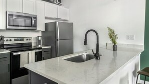 Uma cozinha moderna com eletrodomésticos de aço inoxidável, bancada de mármore e torneira preta.