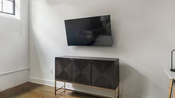 Una habitación con una televisión de pantalla plana montada en la pared y un mueble de madera oscura con un diseño geométrico.