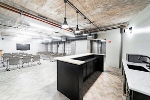 A modern conference room with a large table, chairs, and a kitchen area with a sink and countertop. - Landing Amazing Studio, Gym (Houston)