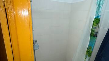 Un baño con ducha, inodoro y una puerta amarilla.