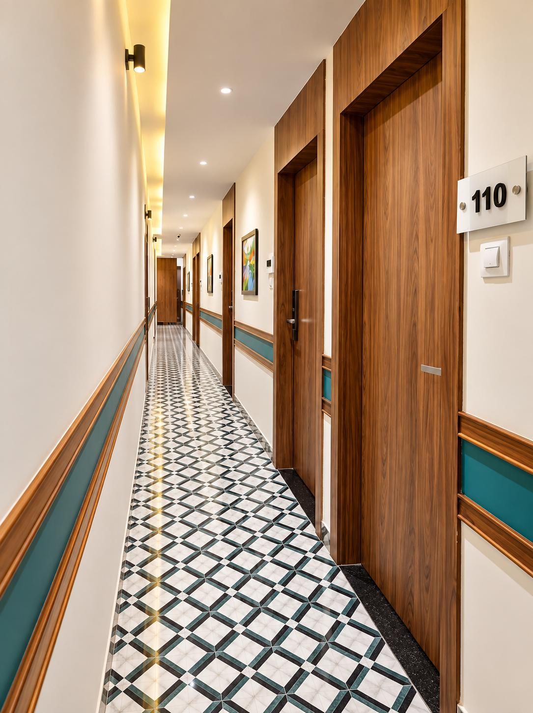 A hotel hallway with wooden doors, numbered room signs, and patterned floor tiles.