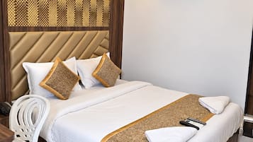 A modern hotel room with a bed, a white chair, a ceiling fan, and an air conditioning unit.