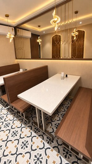 A hotel room with a large bed, a small table, and a bench.
