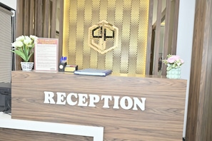 A reception desk with a sign reading 'RECEPTION' and a decorative wall behind it. - HOTEL SHAHI PALACE (Mumbai)
