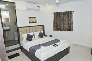 A hotel room with a bed, a bathroom, and a shower area. - HOTEL SHAHI PALACE (Mumbai)