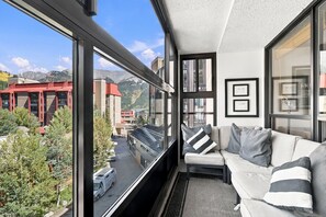 A modern interior with a balcony, a sofa, and a view of a cityscape and mountains. - Mountain Plaza Escape, Hot Tub, Parking, Mountain and Lake Views (Copper Mountain)