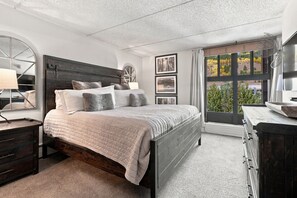 A bedroom with a bed, a dresser, a mirror, and framed pictures on the wall. - Mountain Plaza Escape, Hot Tub, Parking, Mountain and Lake Views (Copper Mountain)
