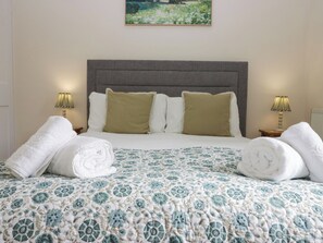 A neatly made bed with a patterned bedspread, two pillows, and rolled towels on either side. - 8 Railway Cottages (Ulverston)