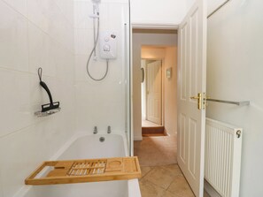 A bathroom with a bathtub, a shower, and a wooden tray. - 8 Railway Cottages (Ulverston)