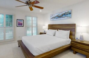 A bedroom with a wooden bed, two bedside tables with lamps, a ceiling fan, and a large window with blinds. - Coastal Charm Near the Beach in Rehoboth (Rehoboth Beach)