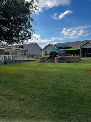 A residential backyard with a barbecue area, a covered patio, and a wooden deck.