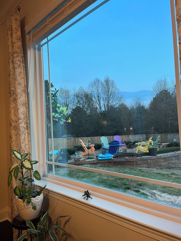 A view through a window with a view of a backyard, including a wooden fence, trees, and outdoor furniture.