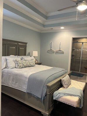 A bedroom with a large bed, bedside tables, a bench, and a walk-in closet.
