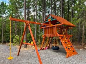 Une aire de jeux avec des balançoires et une structure d’escalade.