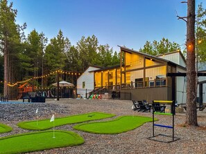 Ein Gebäude mit einer Terrasse und Außenbereich zum Sitzen, umgeben von Bäumen und einem kleinen Putting-Green.