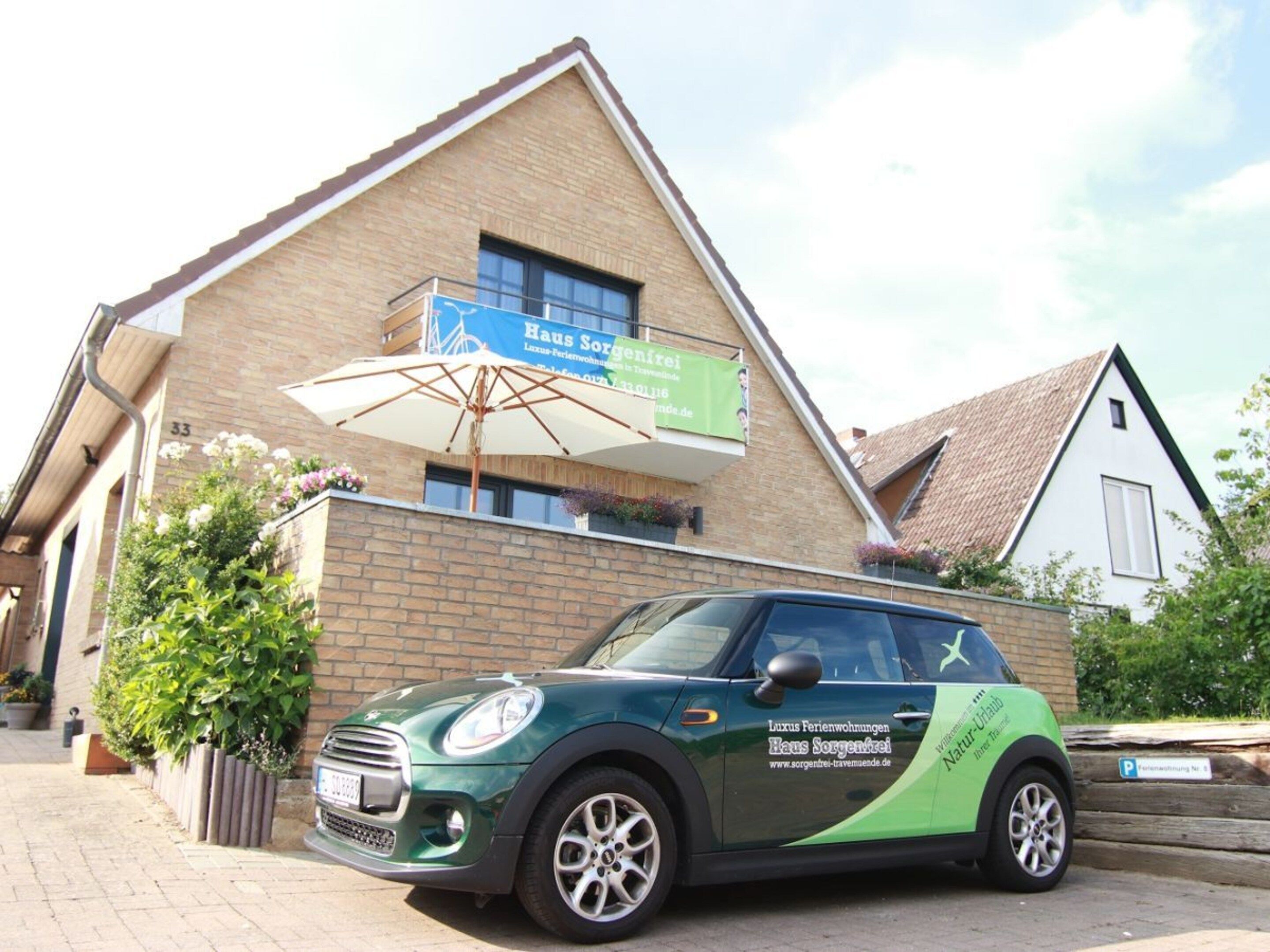 A green car parked in front of a building with a sign that reads 'Haus Sorgenfrei.'