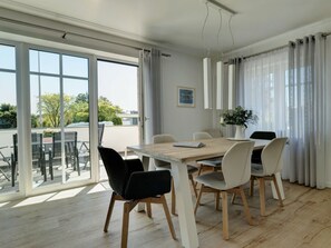 Ein moderner Essbereich mit Holztisch und Stühlen, großen Fenstern und Blick ins Freie.