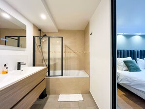 A modern bathroom with a glass shower enclosure, a bathtub, and a vanity with a mirror. - Opera Apartment in the Heart of Paris (Paris)