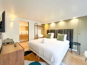 A hotel room with a large bed, bedside tables, a TV, and a bathroom with a mirror and towel rack. - Opera Apartment in the Heart of Paris (Paris)