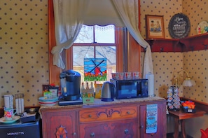 A kitchen with a coffee maker, microwave, and a window with a stained glass view.