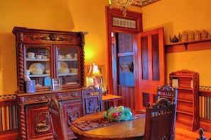 A traditional dining room with a wooden cabinet, a table with chairs, and a decorative centerpiece.