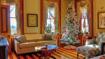 Un salon chaleureux avec un plancher en bois, un canapé, un fauteuil et un sapin de Noël.